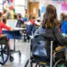 students in wheelchairs attending inclusive classroom with teacher in background
