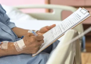 hospital patient filling out medical form while resting with iv attached