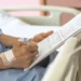 hospital patient filling out medical form while resting with iv attached
