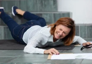 woman falling on stairs while holding papers in pain