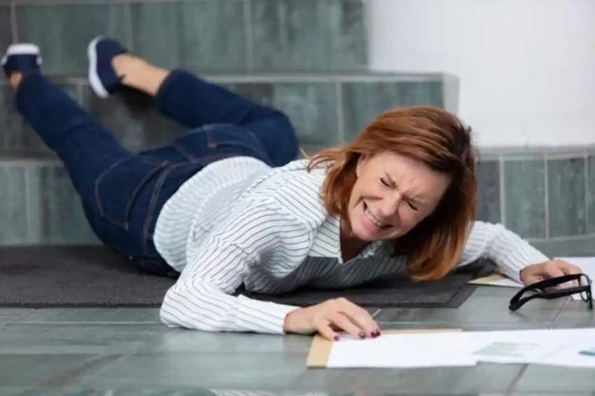 woman falling on stairs while holding papers in pain