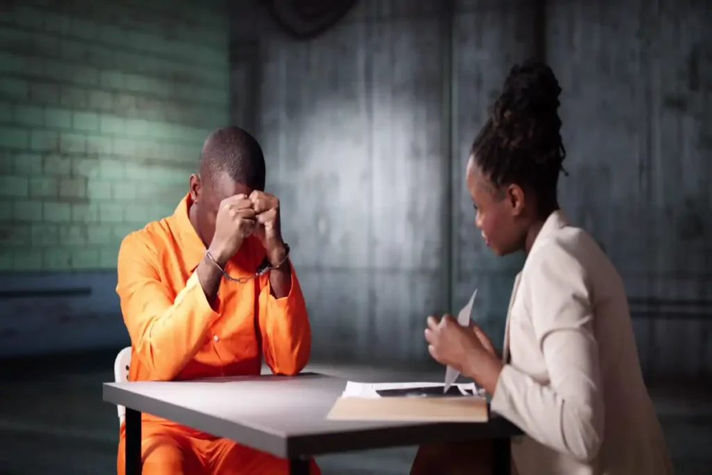 handcuffed man in jail uniform meeting with legal counselor